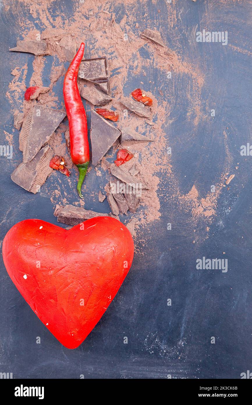 red symbol of heart and chili peppers and dark chocolate pieces on