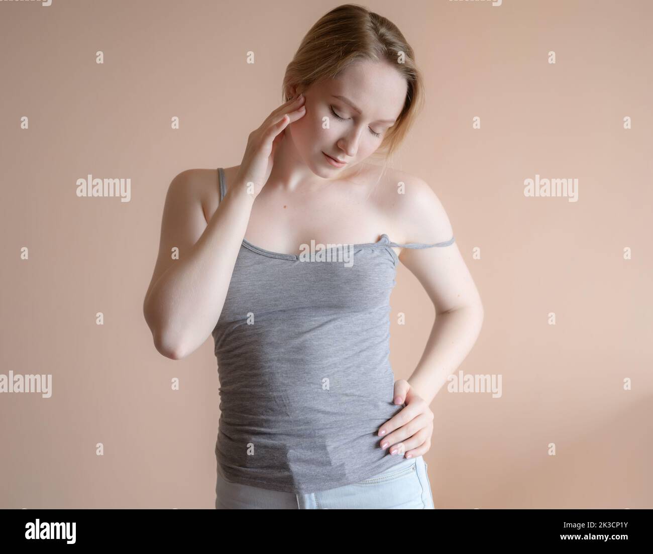 Graceful young woman posing against beige wall. Stock Photo