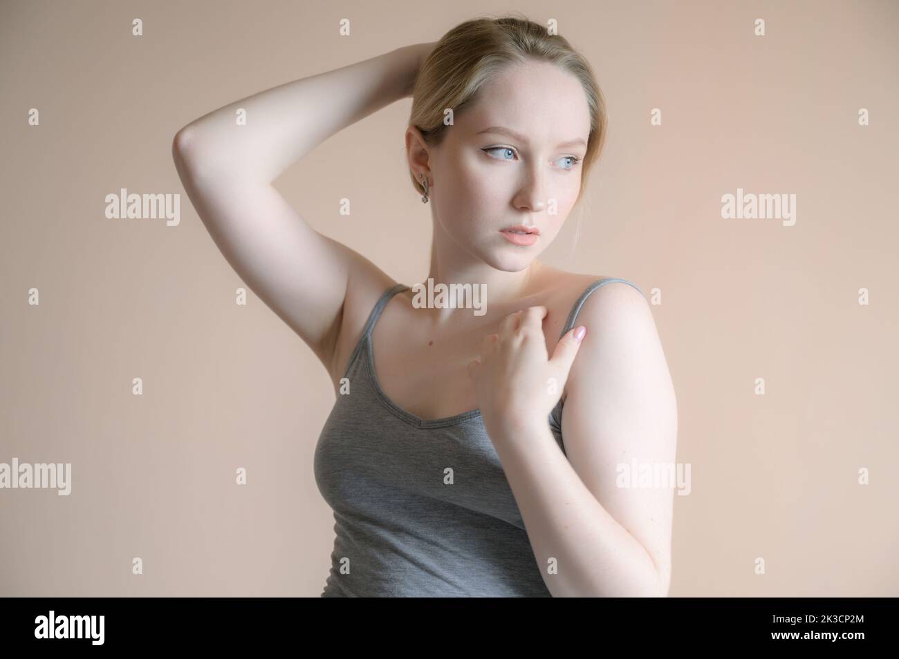 Graceful young woman posing against beige wall. Stock Photo