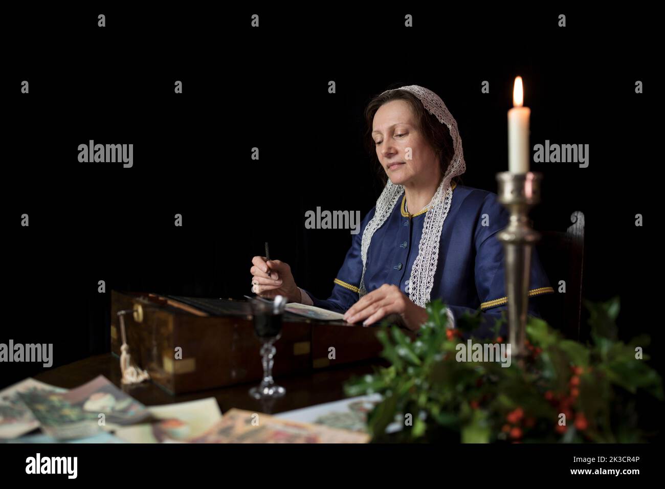 Interpretation of a 19th Century lady writing out a traditional Christmas Greetings card. Stock Photo