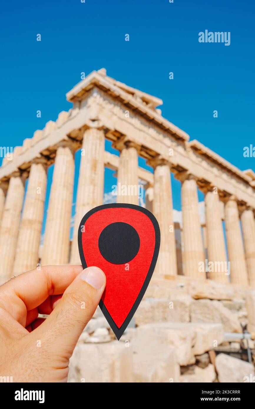 a man holds a red marker that points the remains of the famous Parthenon, in the Acropolis of Athens, Greece Stock Photo
