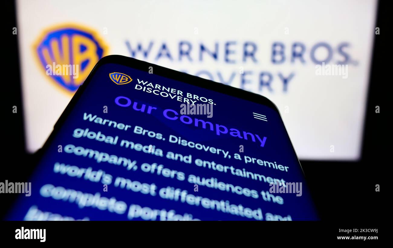 Smartphone with website of US media company Warner Bros. Discovery Inc. (WBD) on screen in front of logo. Focus on top-left of phone display. Stock Photo