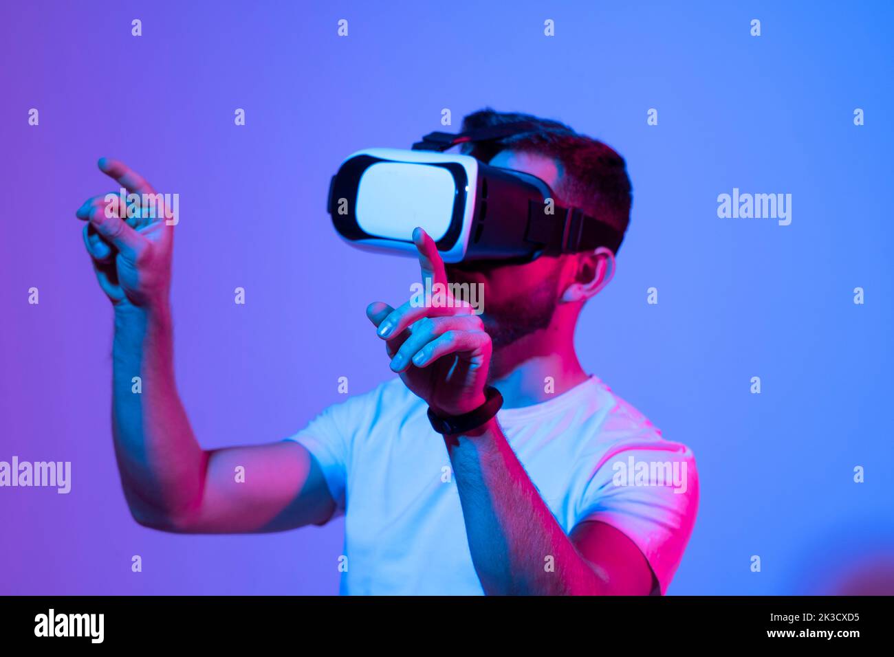 Young bearded man playing virtual reality game using VR goggles. Stock Photo