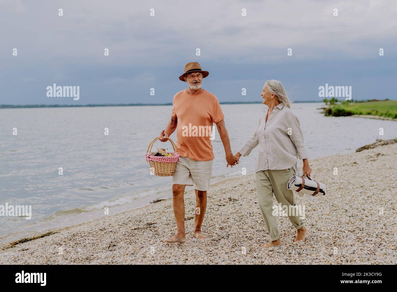 Senior couple walking with picnic basket near the river. Stock Photo