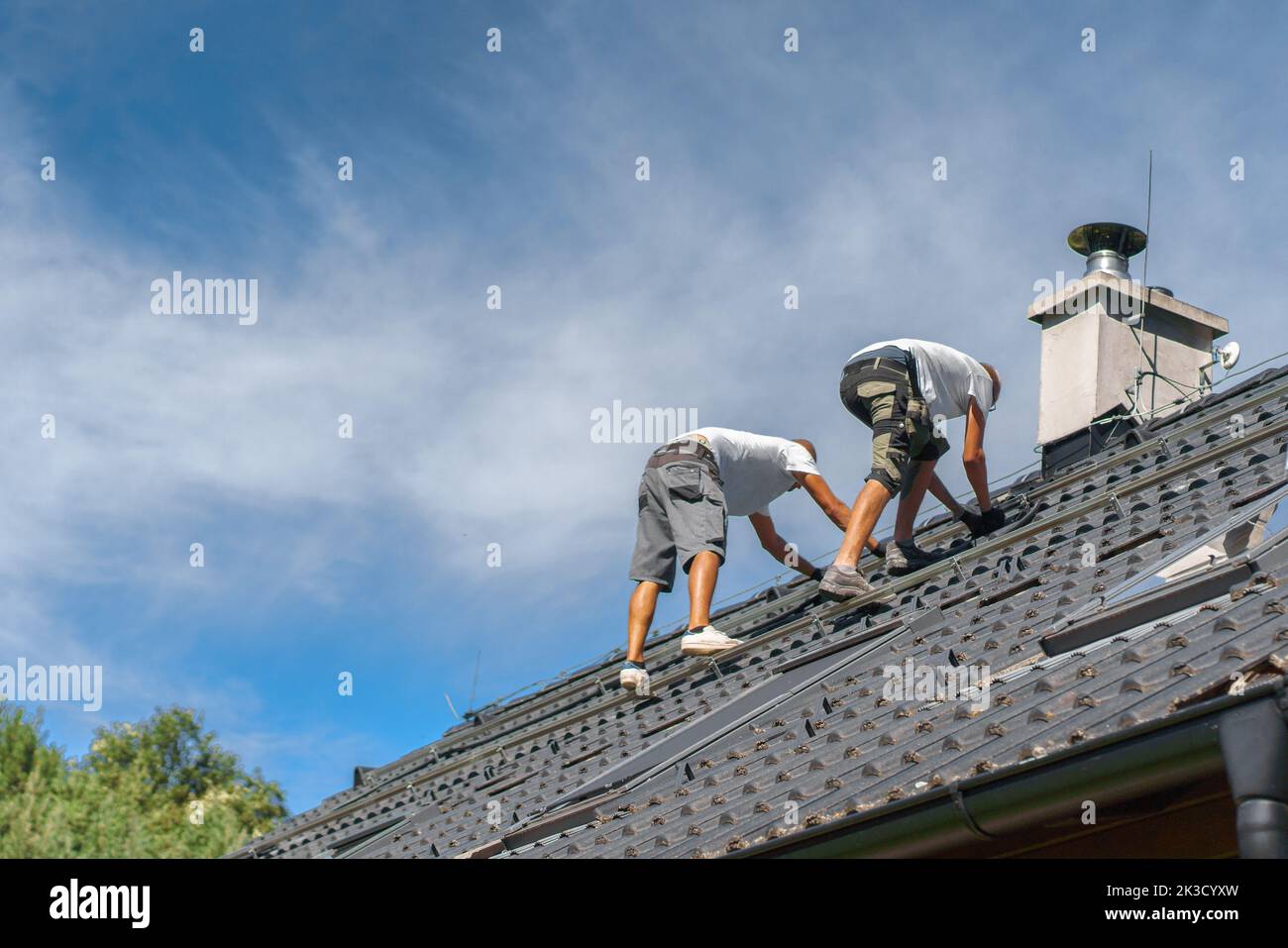 Men worker installing solar photovoltaic panels on roof, alternative energy, saving resources and sustainable lifestyle concept. Stock Photo
