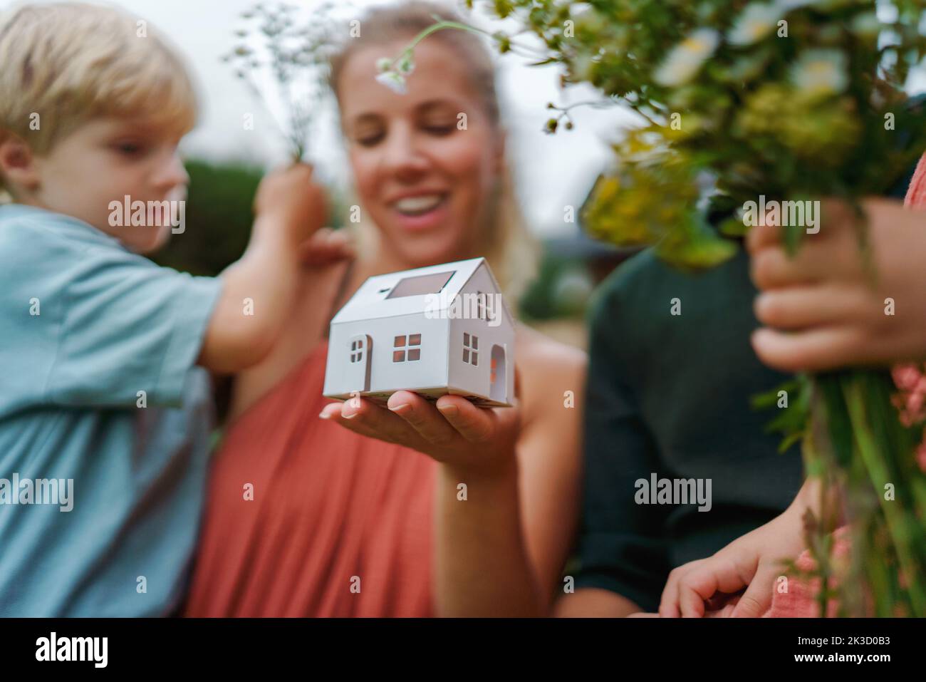 Close up of young mother holding paper model of house with solar panels.Alternative energy, saving resources and sustainable lifestyle concept. Stock Photo