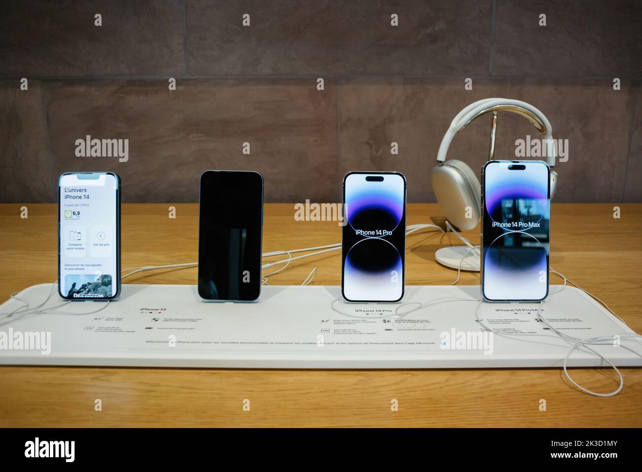 Paris, France - Sep 22, 2022: Front view of new Apple Computers iPhone 4 Pro Plus Max in a row with AirPods Max Bluetooth over-ear headphones - Stock Photo