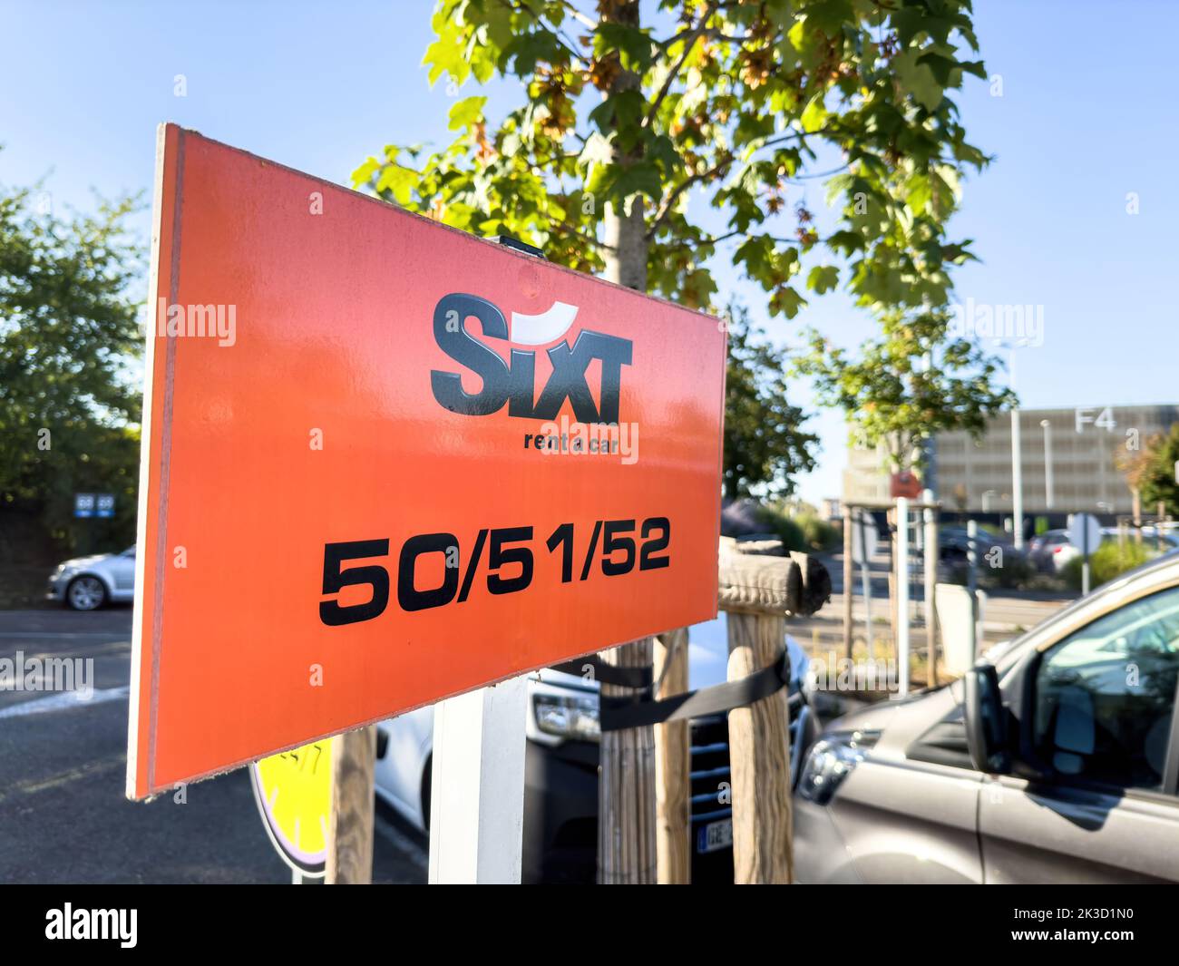 Basel, Switzerland - Sep 22, 2022: Orange sign in large parking with Sixt car rental company logotype with cars vans in background parking of large international Airport Stock Photo
