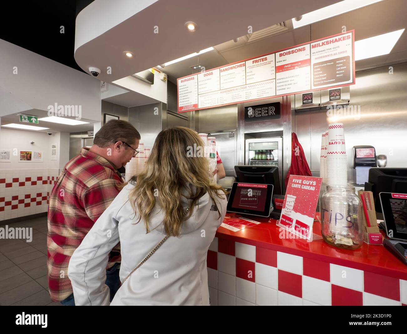 Paris, France - Sep 21, 2022: Customers at the counter reading the menu above Five Guys American fast food restaurant chain with focused on hamburgers, hot dogs, and French fries, and headquartered in Lorton, Virginia, part of Fairfax County. Stock Photo