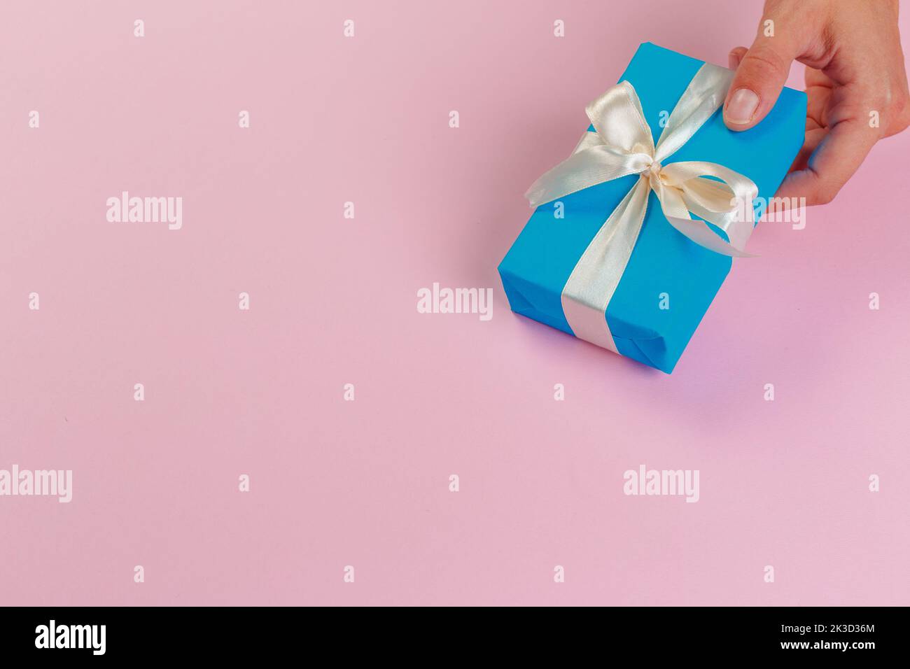 Woman holding gift box on color background Stock Photo - Alamy