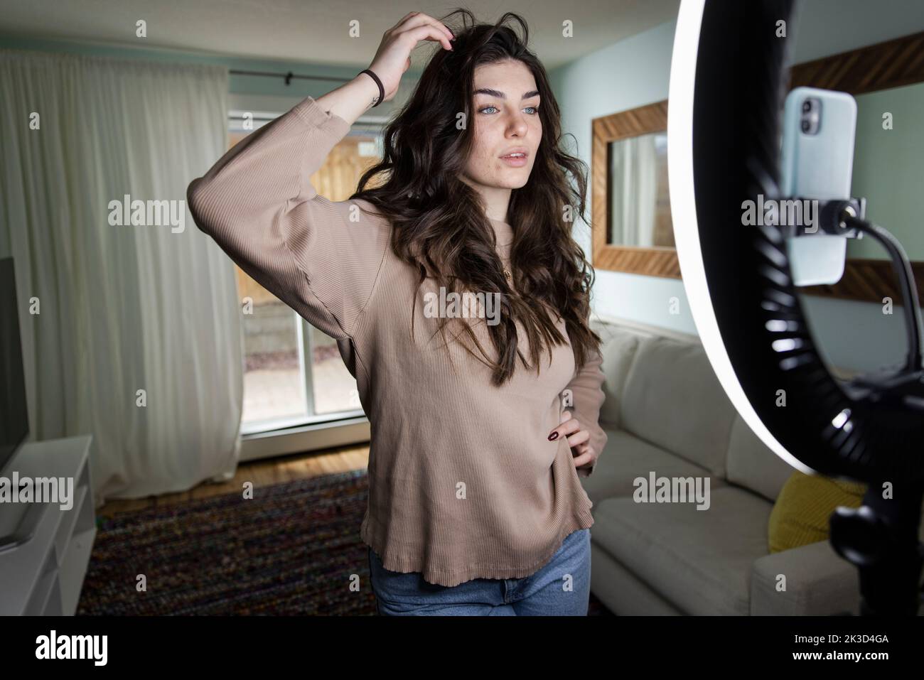 Beautiful young female influencer vlogging in living room at home Stock