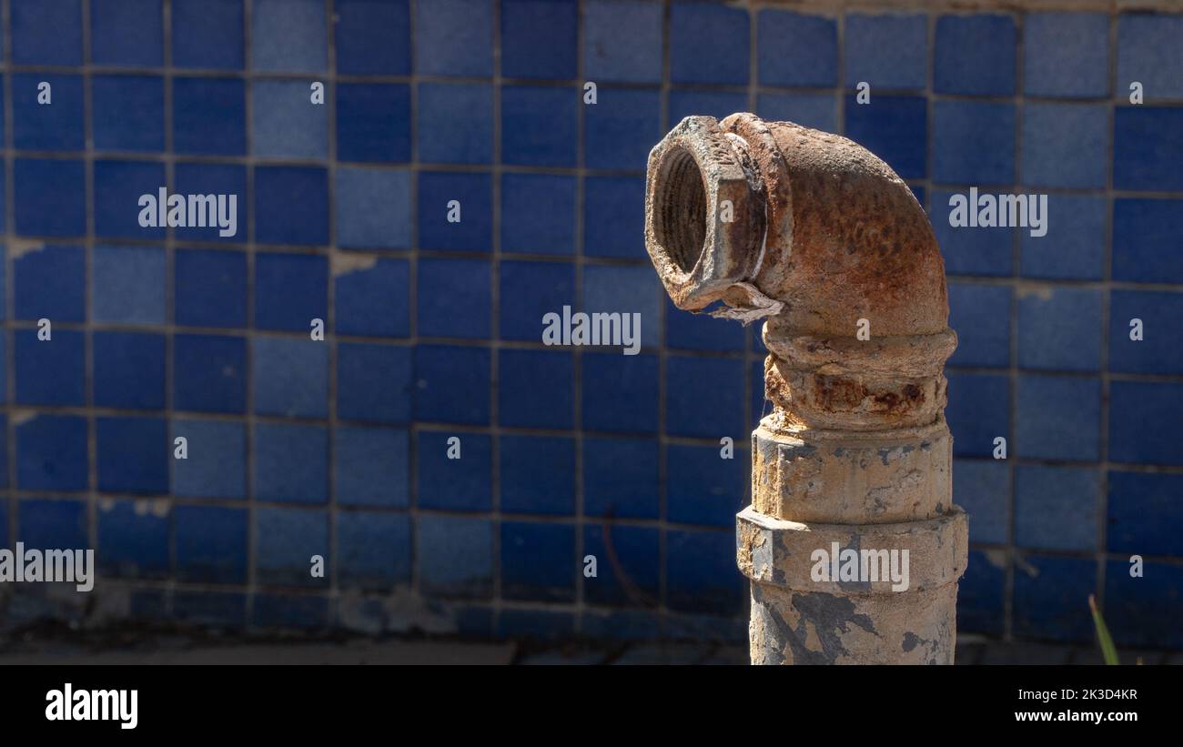 Metal rusty pipe on the background of blue facing tiles Stock Photo