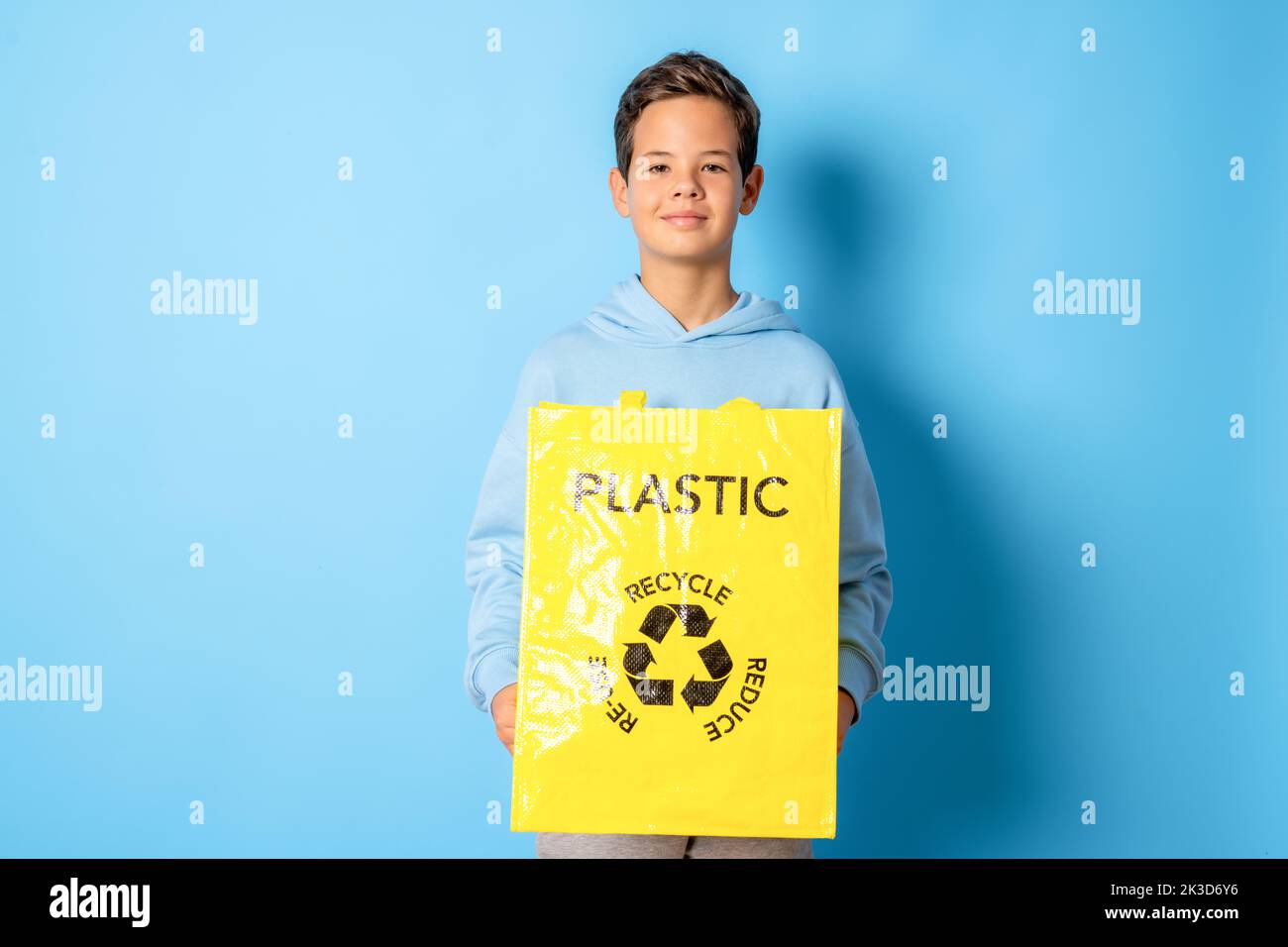 Child boy holding recycling plastic bag standing isolated over blue