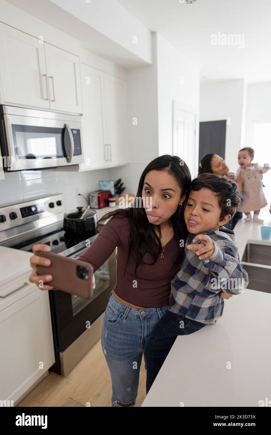 Playful mother and son making a face, taking selfie with smart phone Stock Photo