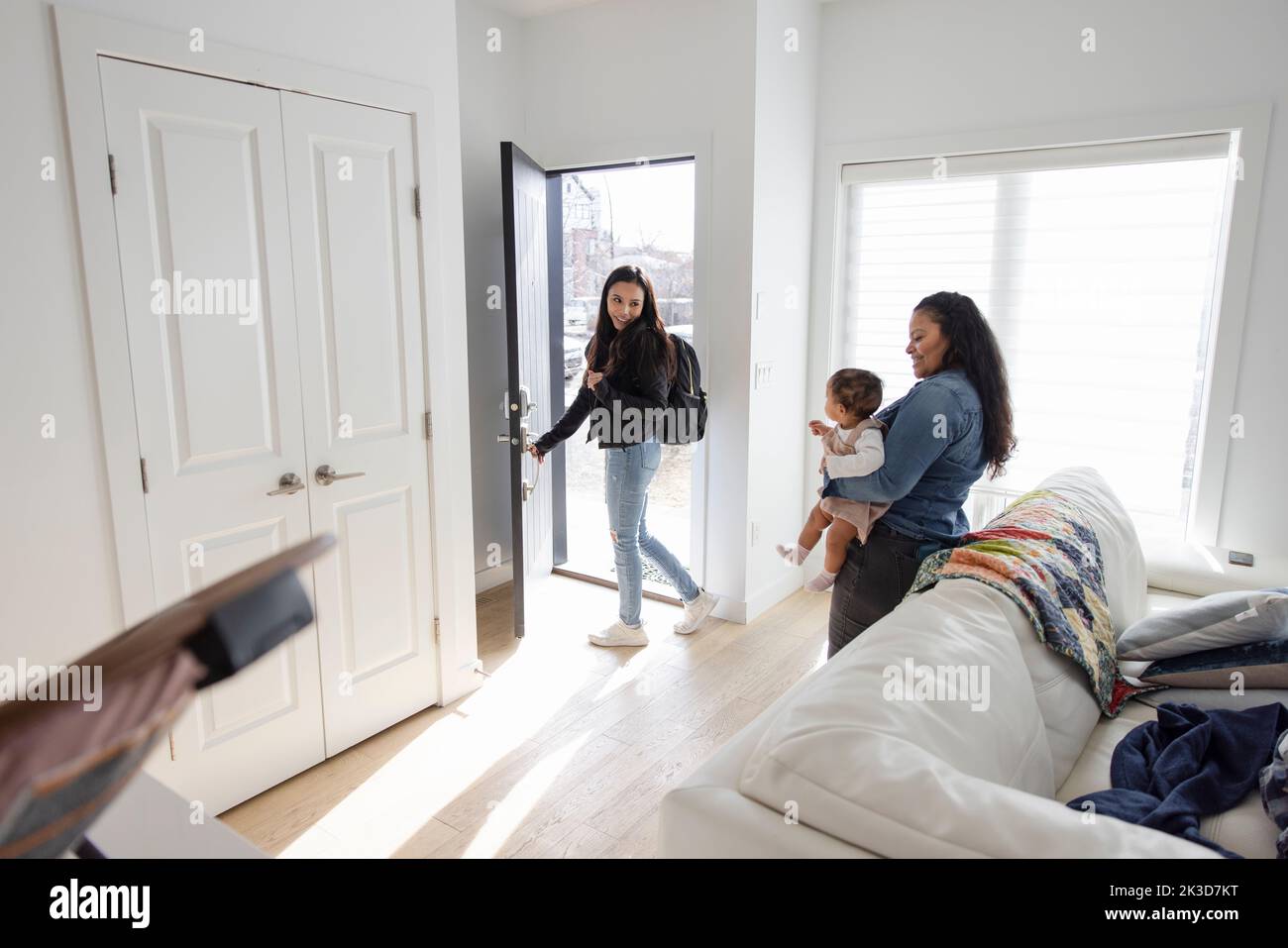 Woman with backpack leaving baby daughter and mother at home Stock Photo