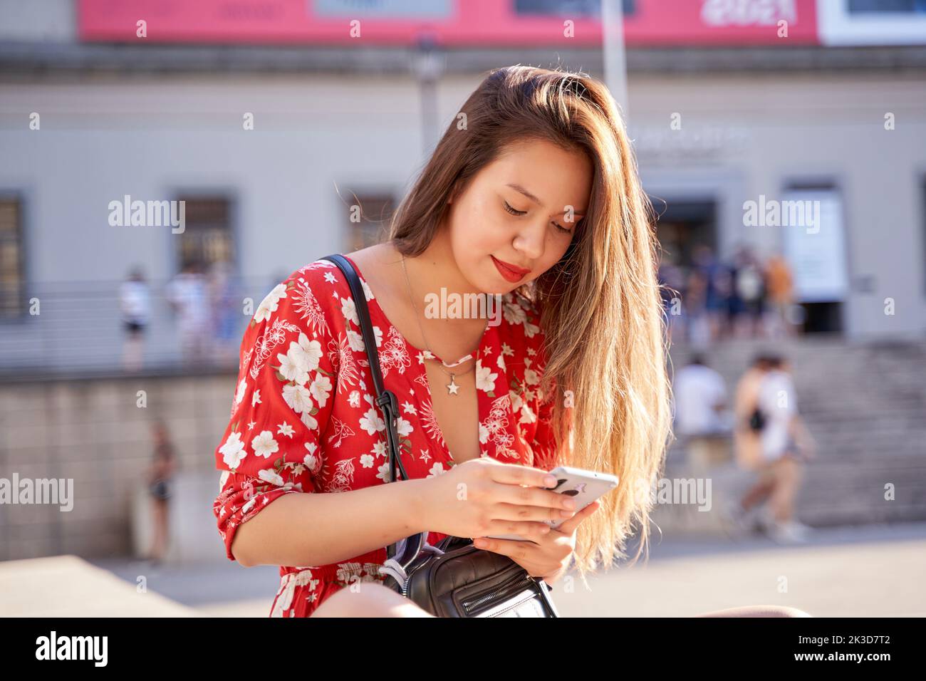 young latina woman with long blonde hair using her smart phone for social networking Stock Photo