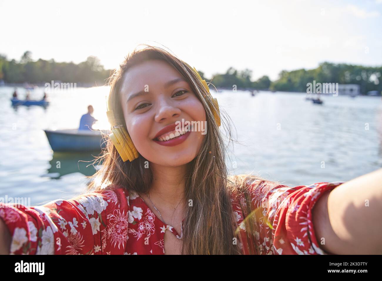 young latina taking a selfie with boats in the background. smiling tourist woman with white teeth and long hair. Stock Photo