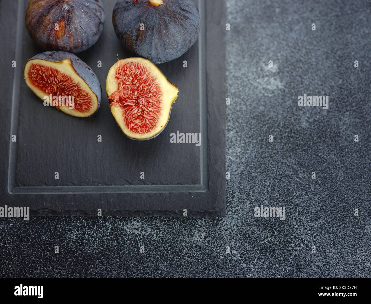 fresh ripe figs fruit and olive branch on dark table. mediterranean