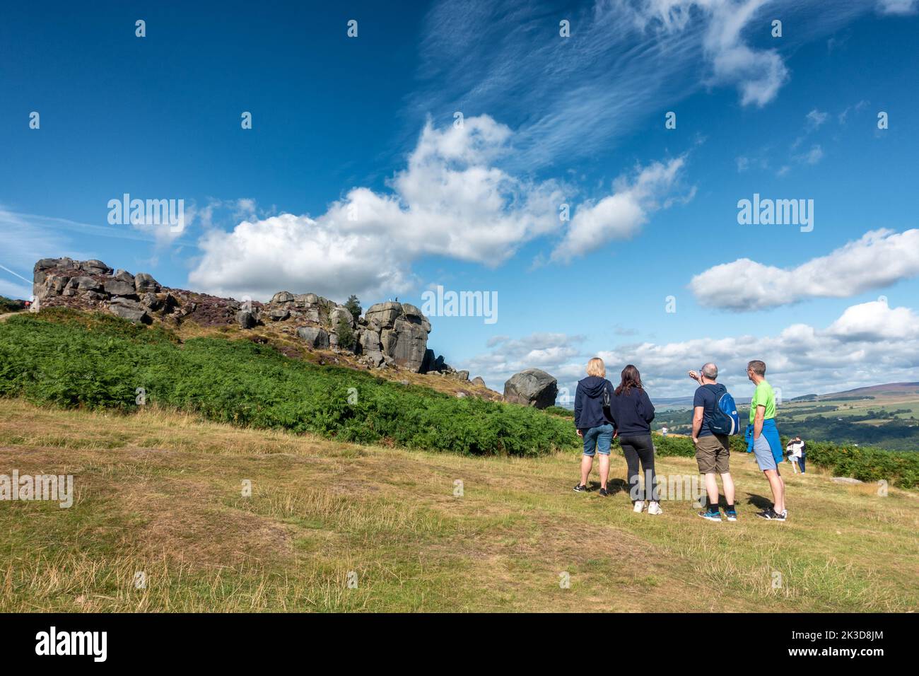 Group of people admiring the Cow and Calf Rocks on Ilkley Moor on a summer's day in West Yorkshire, England, UK Stock Photo