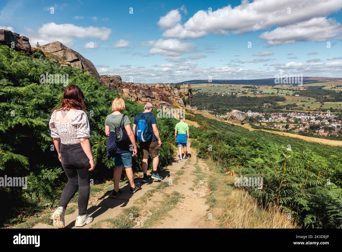 Group of people walking down a path towards the Cow and Calf Rocks on Ilkley Moor on a summer's day, West Yorkshire, England, UK Stock Photo