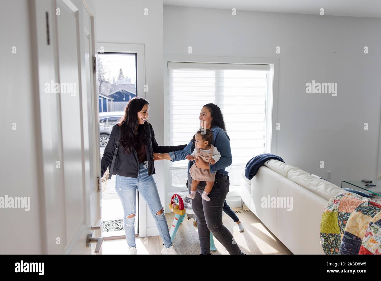 Smiling woman leaving baby daughter with mother at home Stock Photo