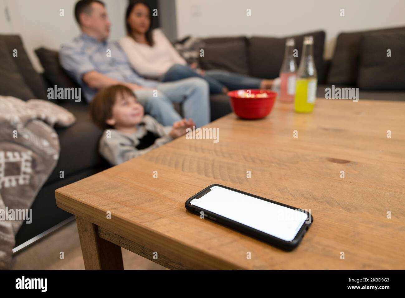 Family watching TV on sofa behind smart phone on coffee table Stock Photo Alamy
