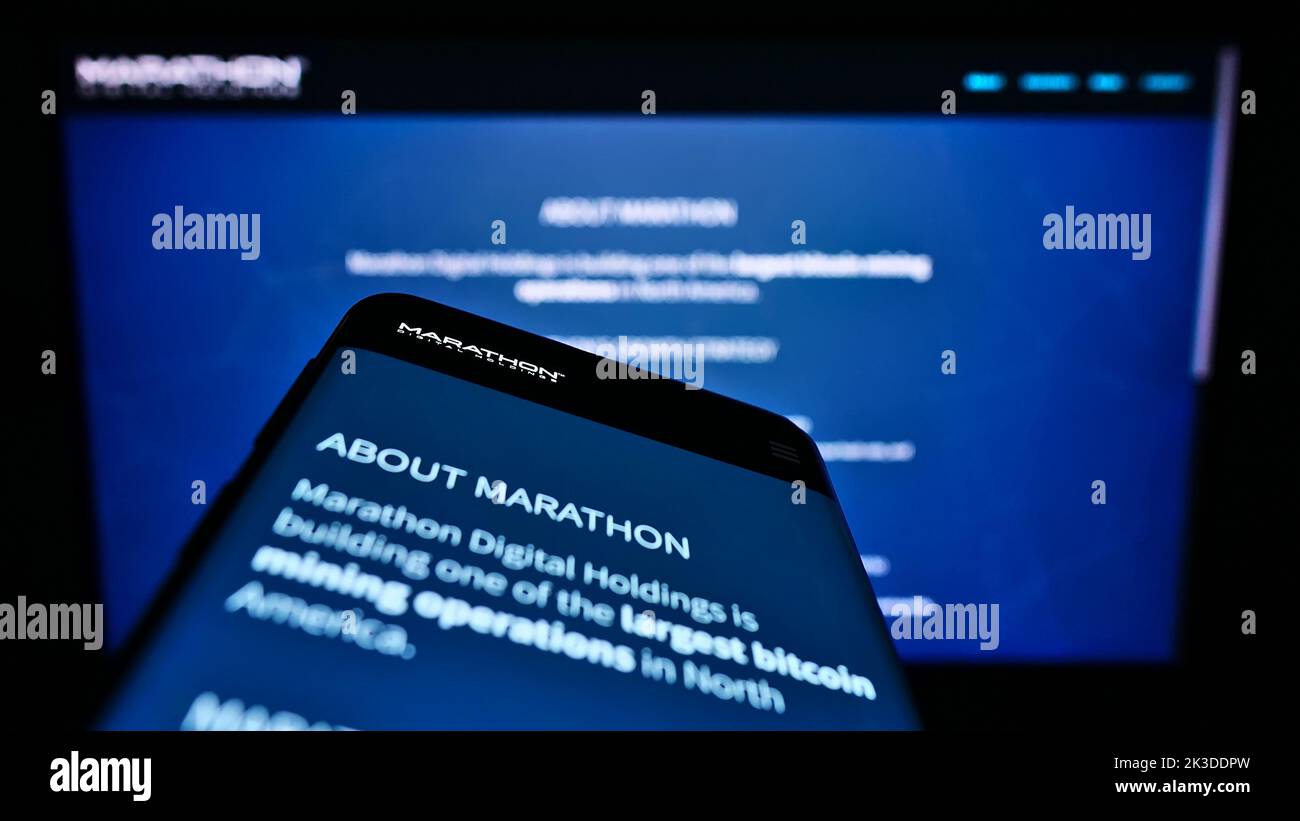Mobile phone with webpage of American company Marathon Digital Holdings Inc. on screen in front of logo. Focus on top-left of phone display. Stock Photo