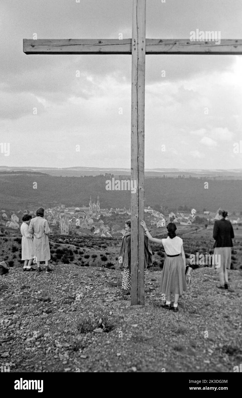 Blick auf Prüm in der Eifel mit Frauen am Gipfelkreuz, circa 1952. View of Prüm with women standing beneath a summit cross, Eifel region, around 1952. Stock Photo