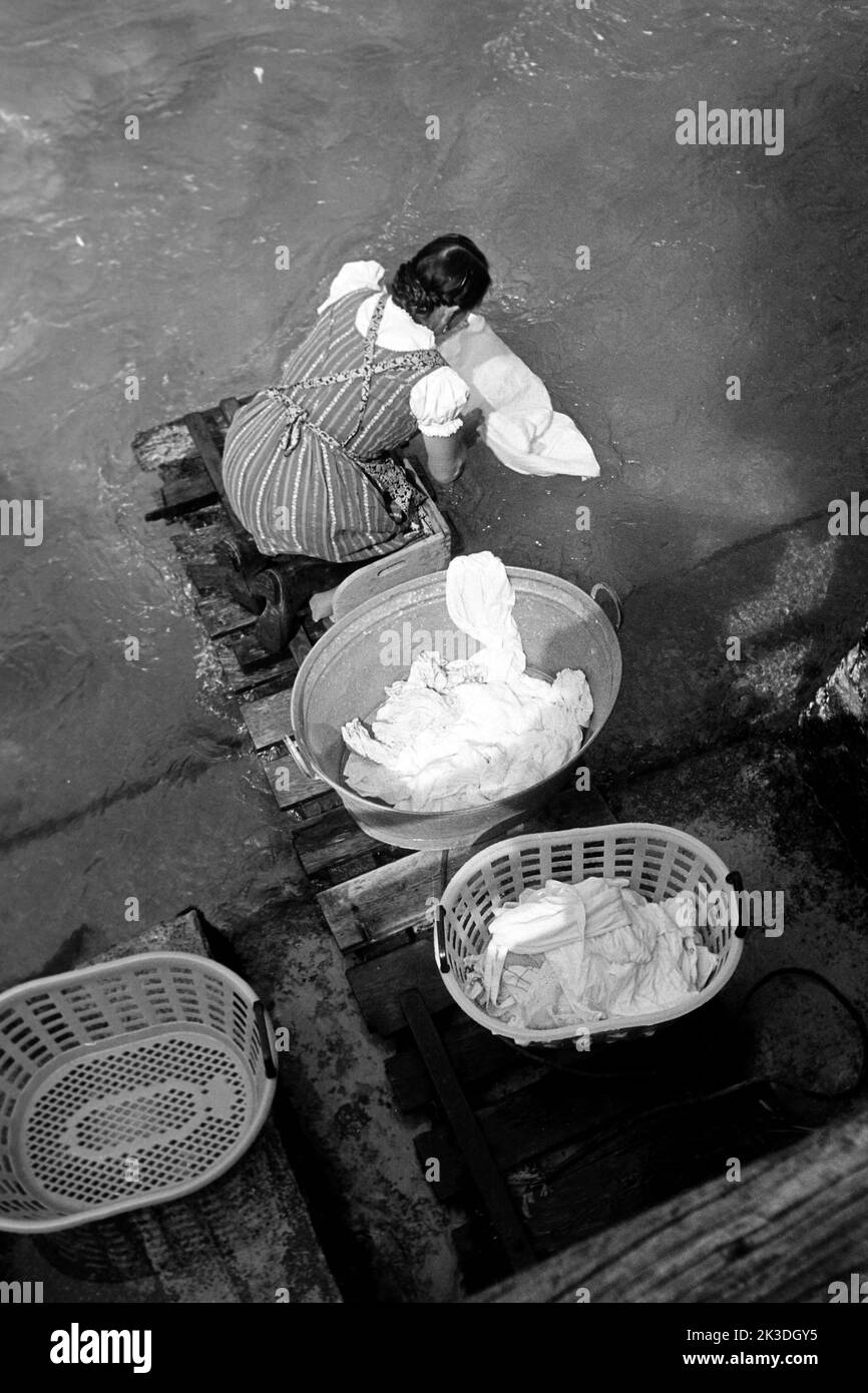 Doing the laundry in the 1960s. A lady is using a washboard to clean the  dirty laundry. The tool was designed for hand washing clothing rubbing them  agains the series of ridges