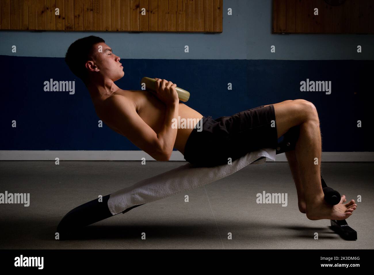 Shirtless 19 year old teenage boy doing situps with extra weight Stock Photo