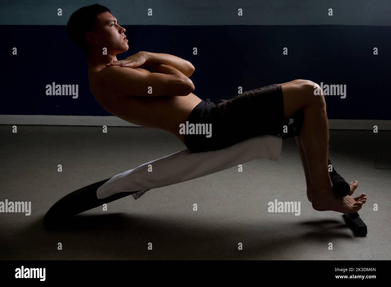 Shirtless 19 year old teenage boy soing situps on an exercise bench Stock Photo