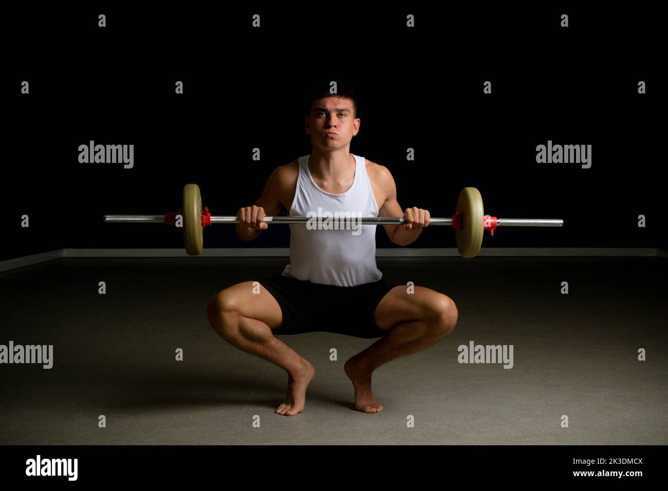 19 year old teenage boy in a tanktop lifting a barbell Stock Photo