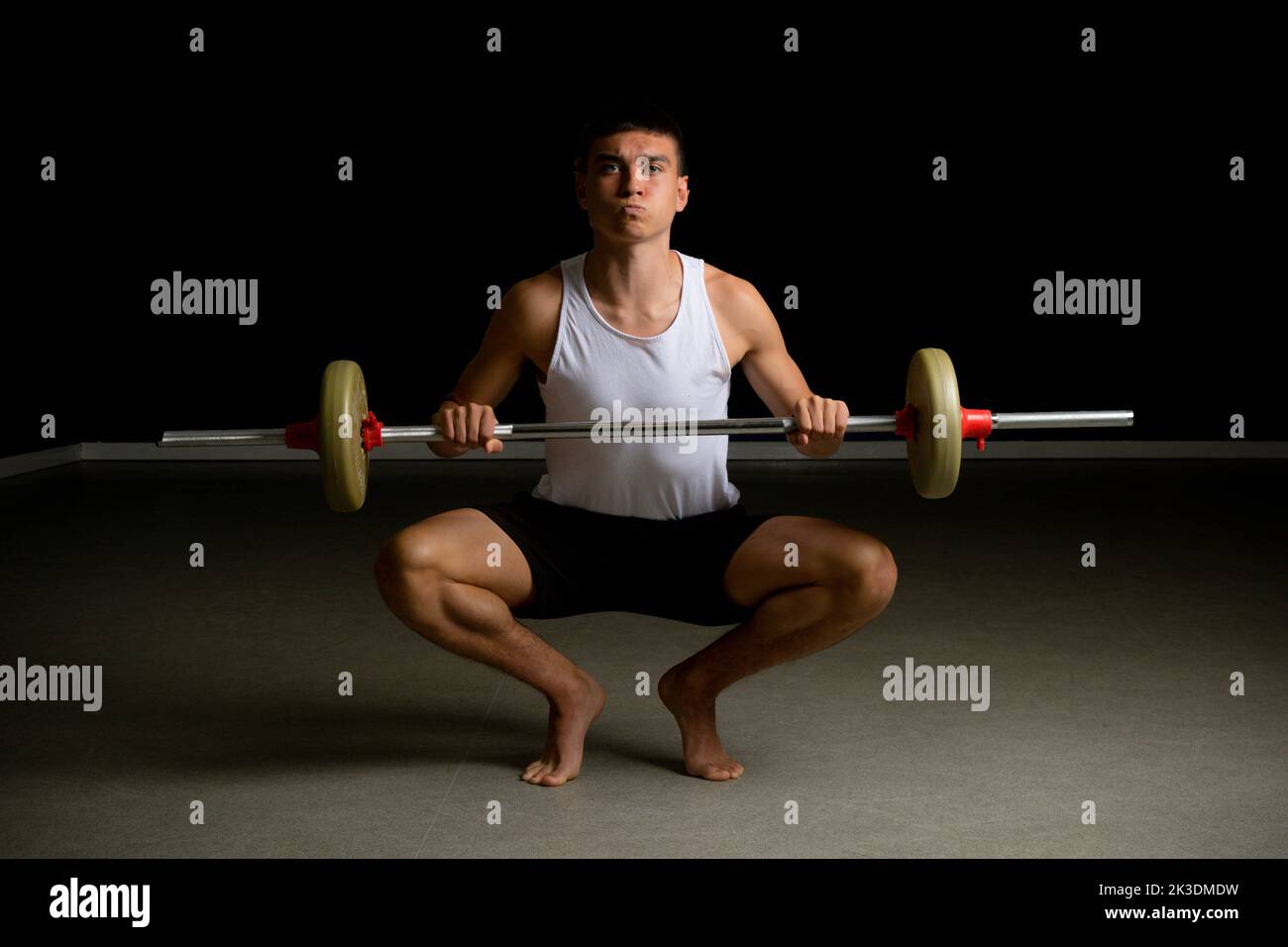 19 year old teenage boy in a tanktop lifting a barbell Stock Photo