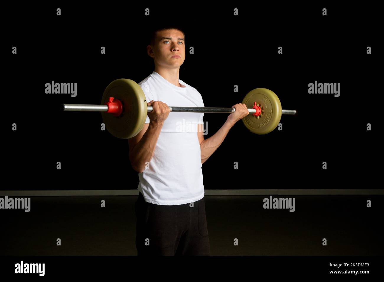 19 year old teenage boy excercising his biceps with a barbell Stock Photo