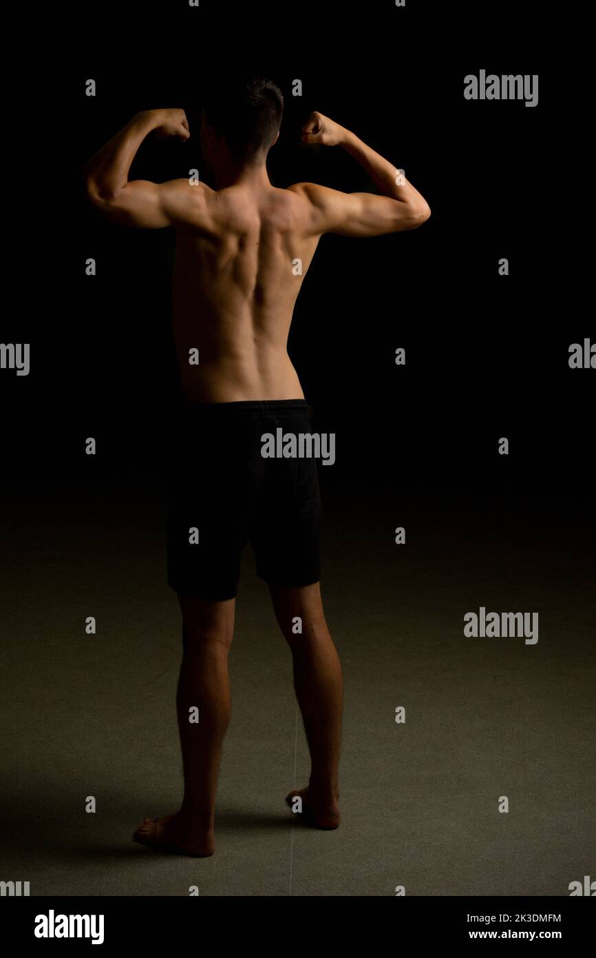 Shirtless 19 year old teenage boy flexing his back muscles Stock Photo