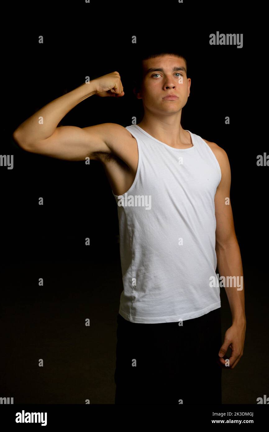 19 year old teenage boy wearing a tank top flexing his arm muscles Stock Photo