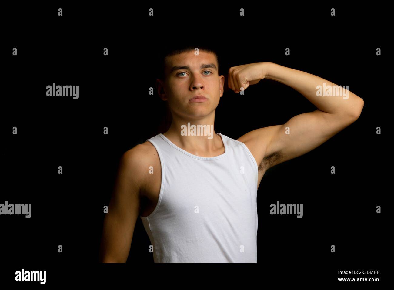 19 year old teenage boy wearing a tank top flexing his arm muscles Stock Photo