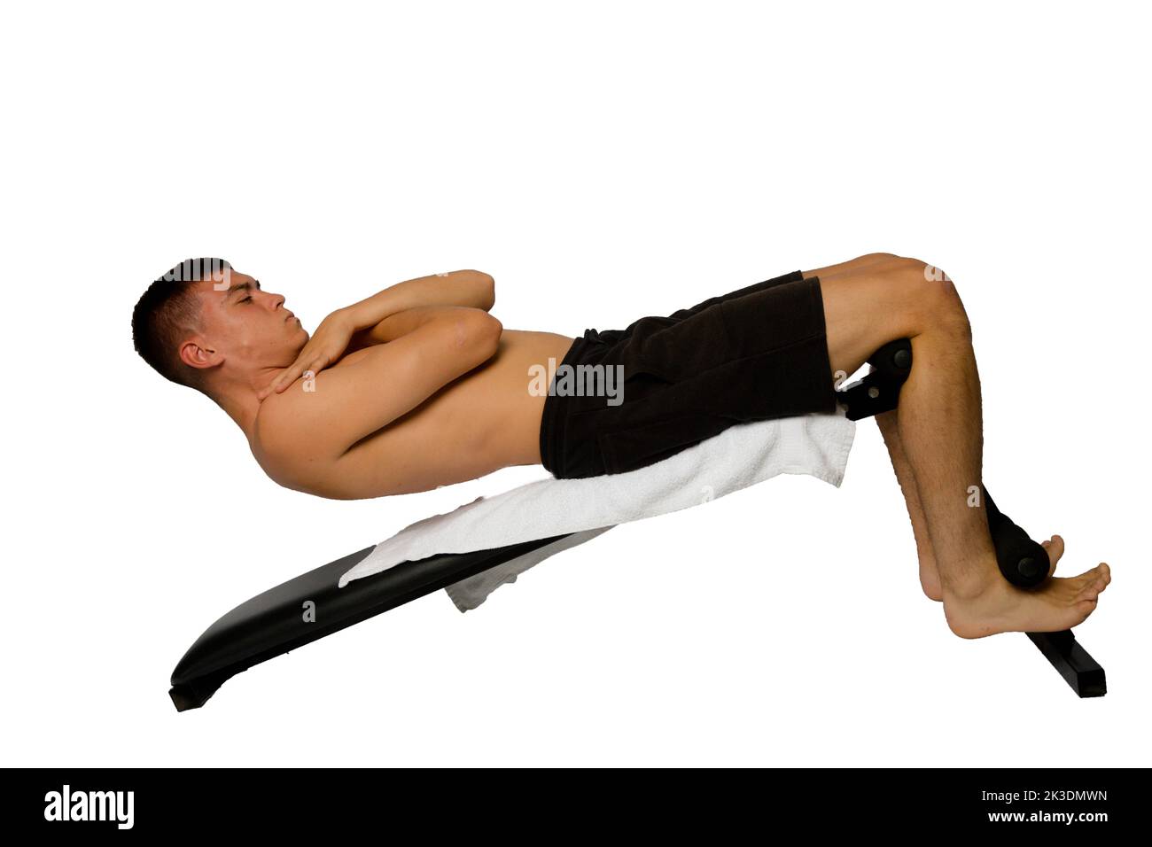 Shirtless 19 year old teenage boy doing sit ups on an exercise bench Stock Photo