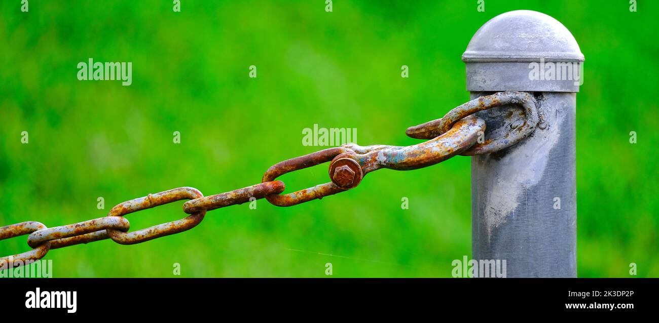 Detail of chain connected to pole for security and protection green background Stock Photo