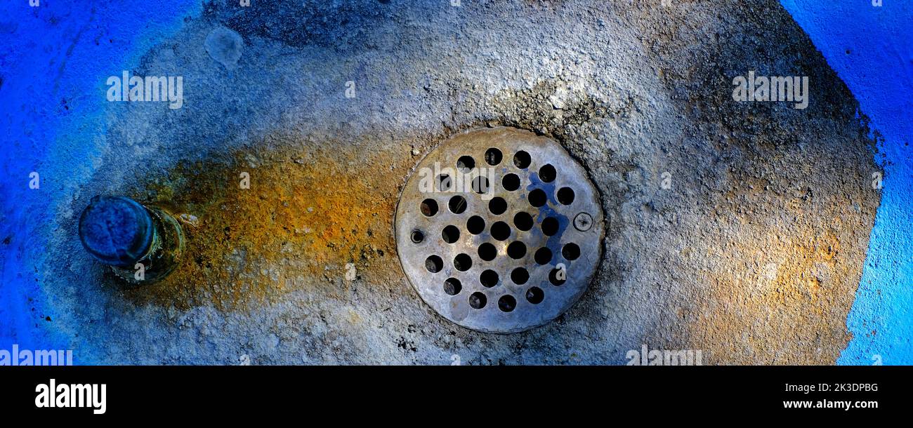 Round metal drain in blue circle sink with stains Stock Photo