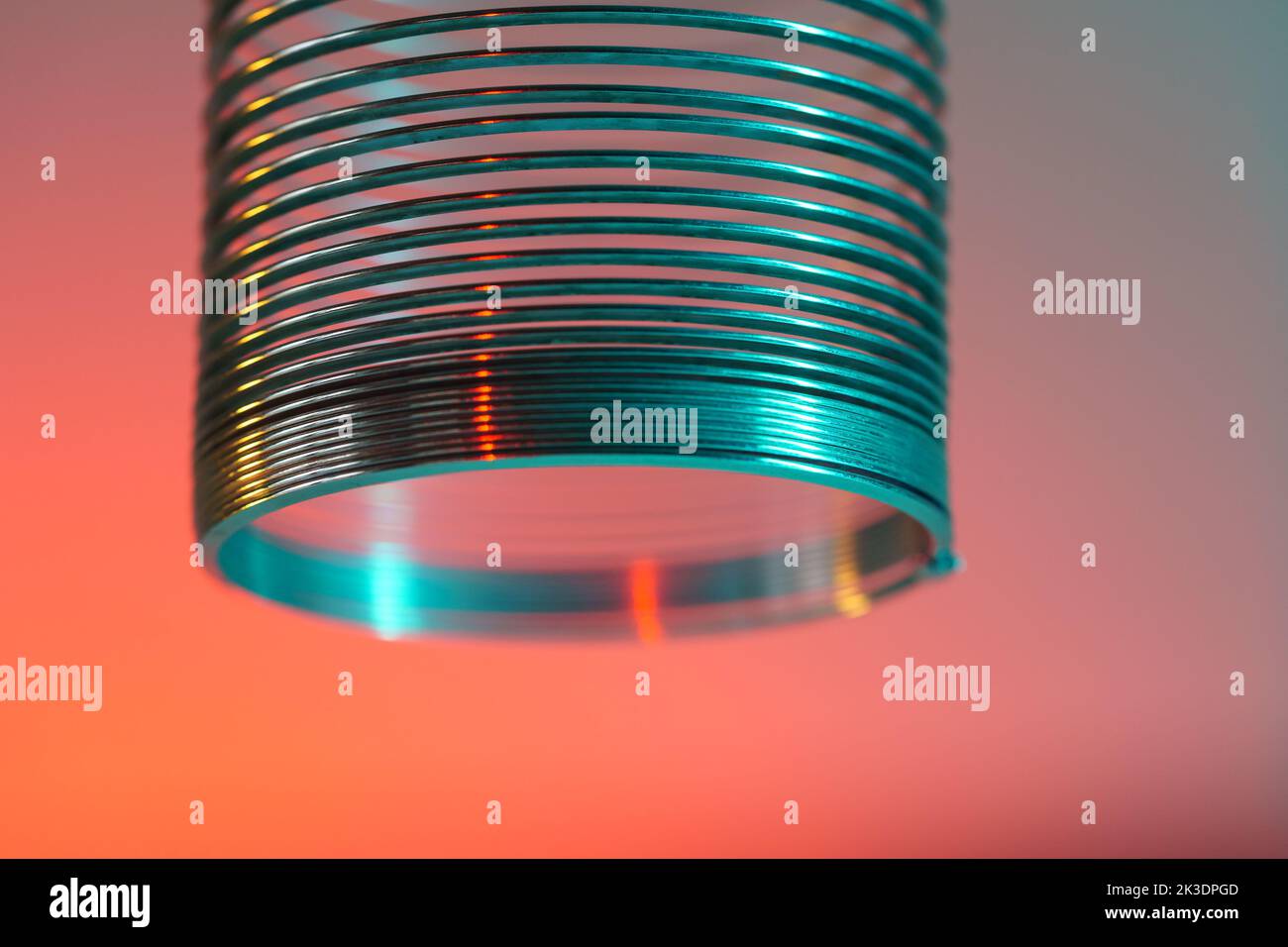 Closeup of coiled metal spring with sufficiently high strength and elastic properties in neon light Stock Photo