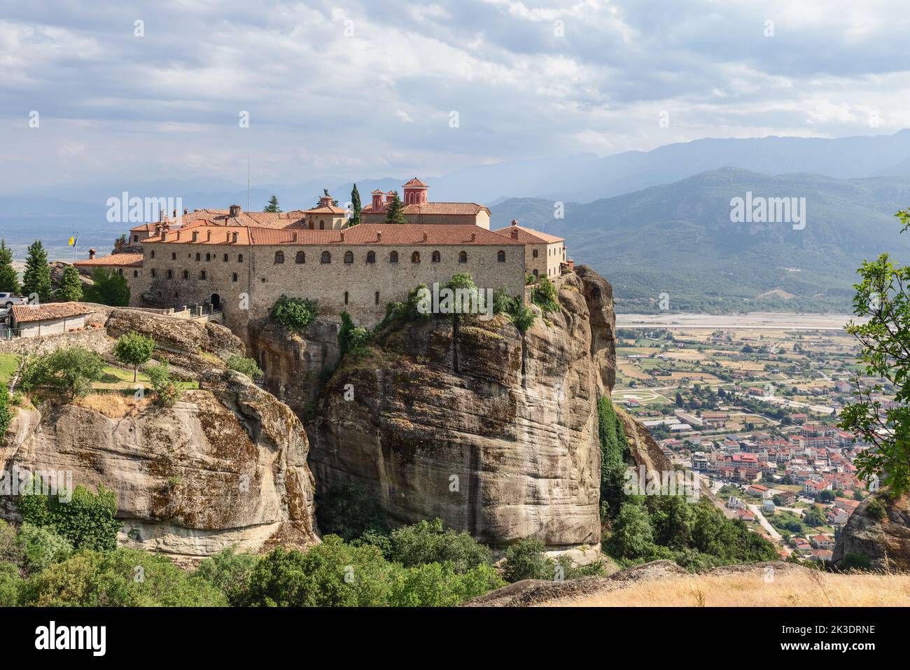 Thessaly valley with Kalambaka city below and Eastern Orthodox St. Stephen Holy Monastery on rock plateau at an altitude of 575 meters. Meteora Stock Photo