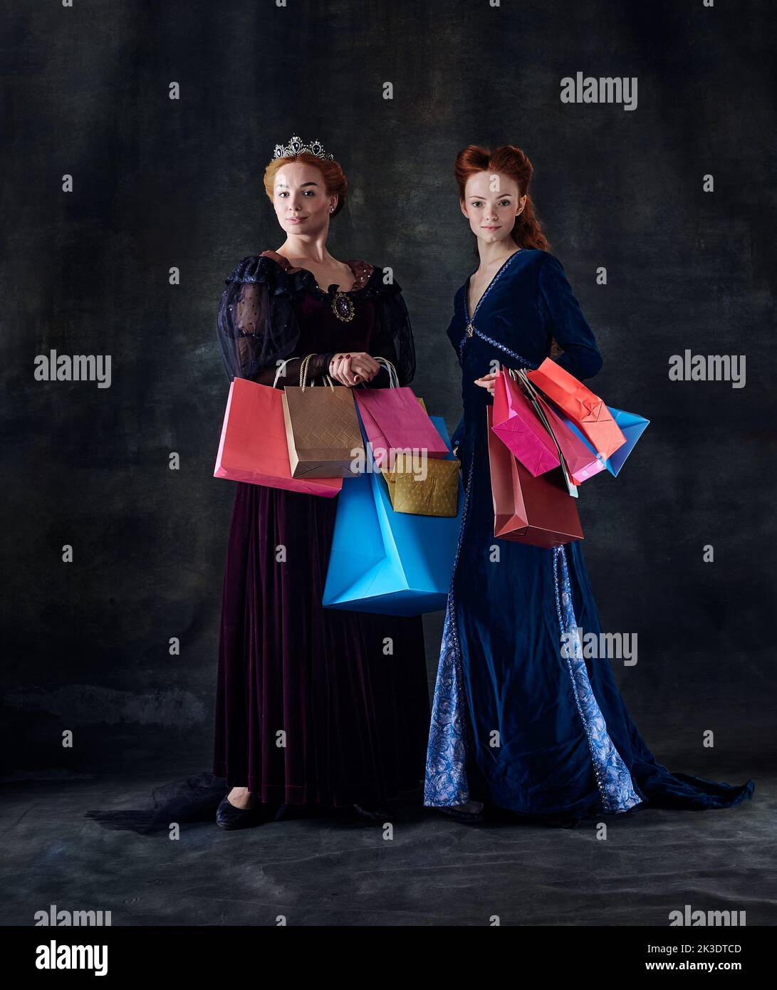 Portrait of two beautiful women in image of queens with many shopping