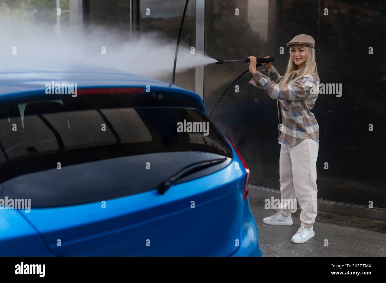 Woman washing a car in a selfservice car wash station with wahing foam