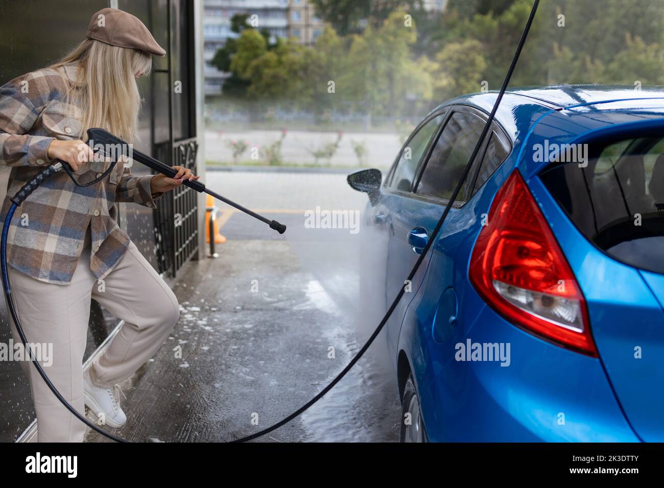Woman washing a car in a selfservice car wash station with wahing foam