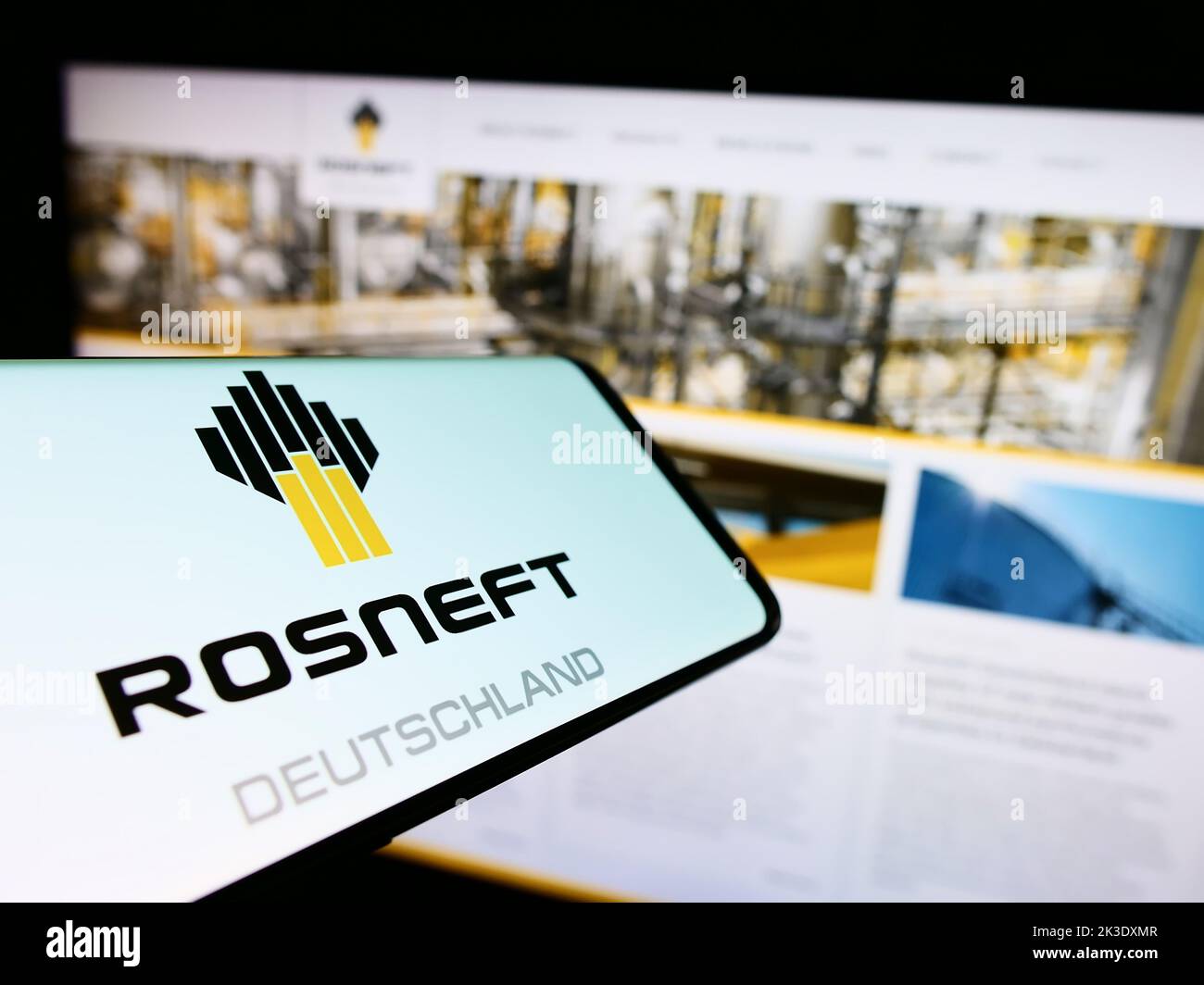 Cellphone with logo of oil refining company Rosneft Deutschland GmbH on screen in front of website. Focus on center-right of phone display. Stock Photo