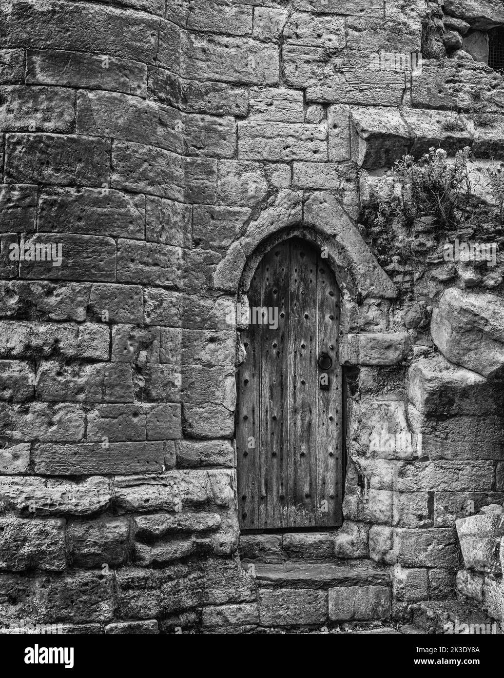 An old wooden door is set in the stonework of a 12th century castle ...