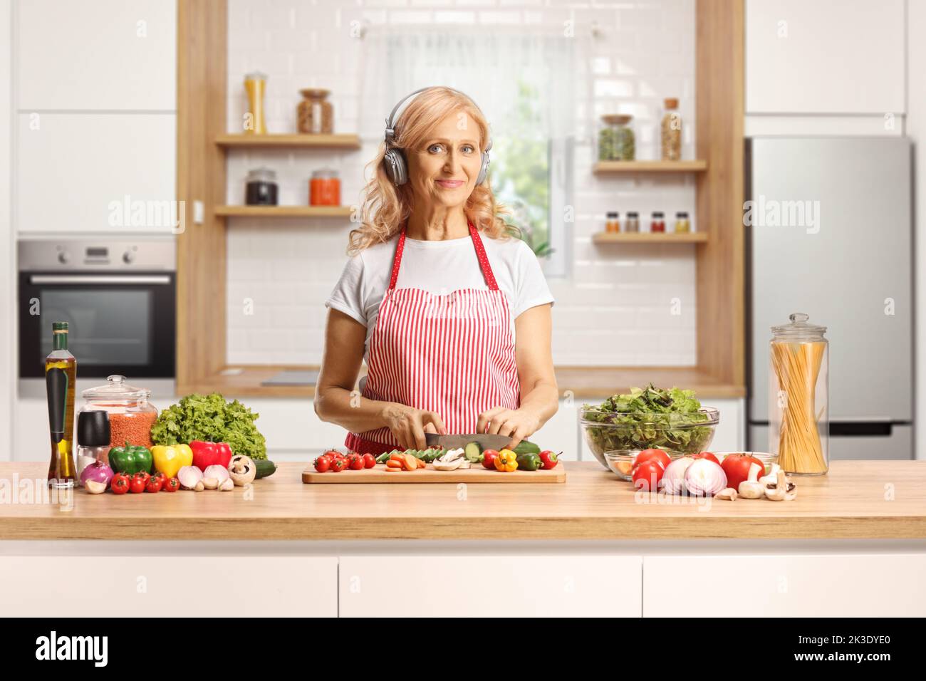 Housewife cooking and listening to music with headphones inside a kitchen Stock Photo