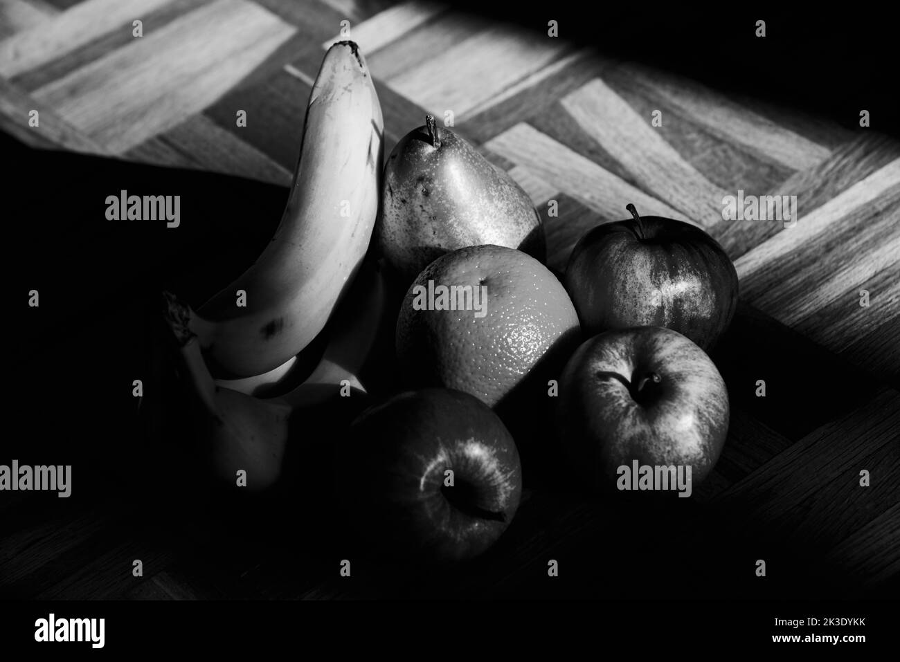 Still life with organic apples, pear, orange banana ripe fruits on vintage wooden surface. Healthy eating background. Black white photography Stock Photo