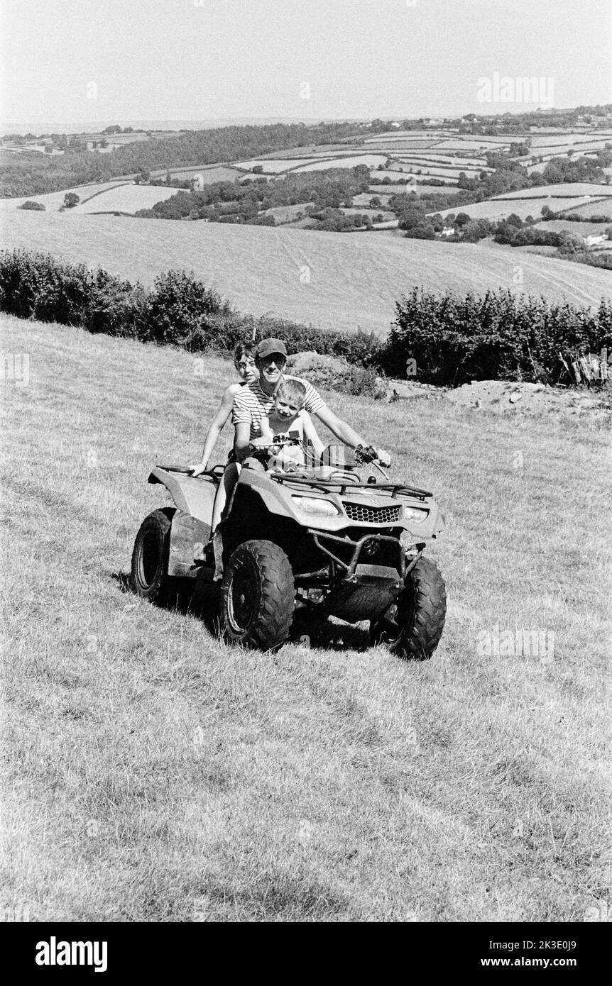 Farmer and two boys riding on a quad bike, High Bickington, North Devon, England, United Kingdom. Stock Photo